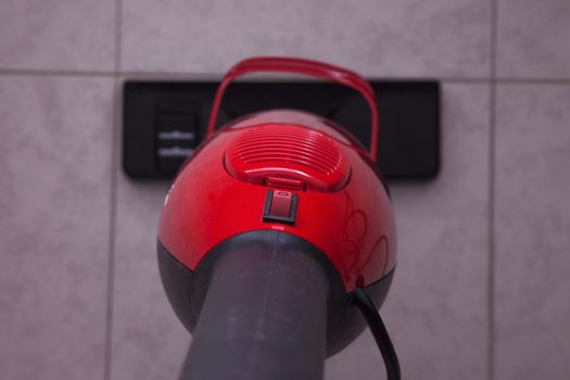 Red vacuum cleaner working over floor, seen from above