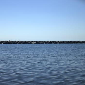 Large stone wall on a blue lake