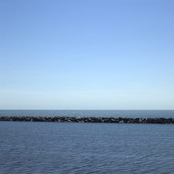Large stone wall on a blue lake