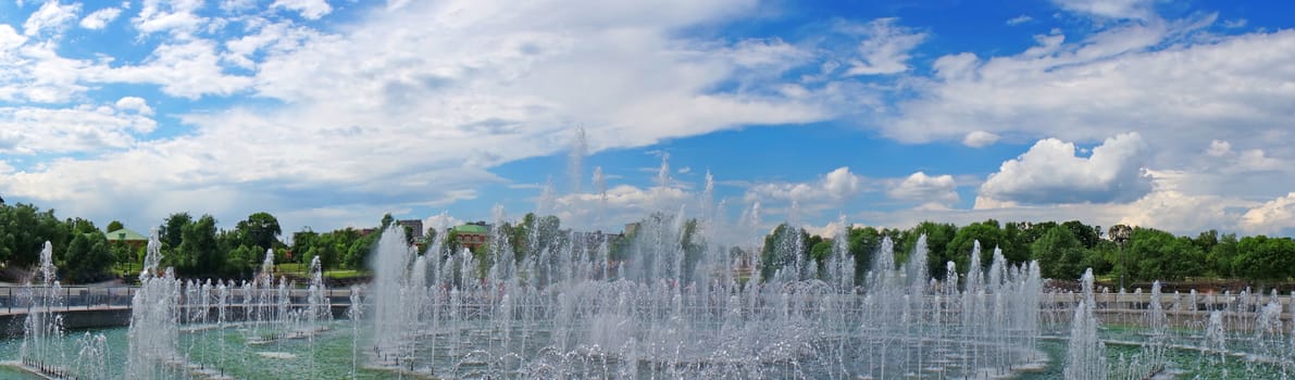 Panorama beautiful fountain against the blue sky with clouds                               