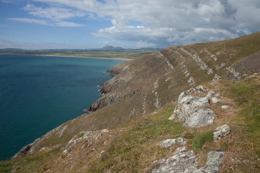 The steep grass banks and cliffs of Cilan Head looking towards the beach at Hell's Mouth, Lleyn peninsular, Gwynedd, Wales, UK.