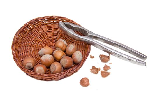 Hazelnuts in a basket with nutcracker on white background