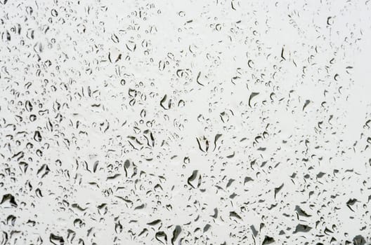 Irregular water drops pattern on glass, close image