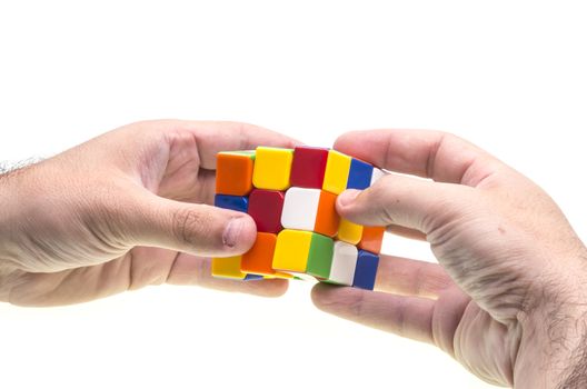 Hands resolving a Rubik's cube over white.
