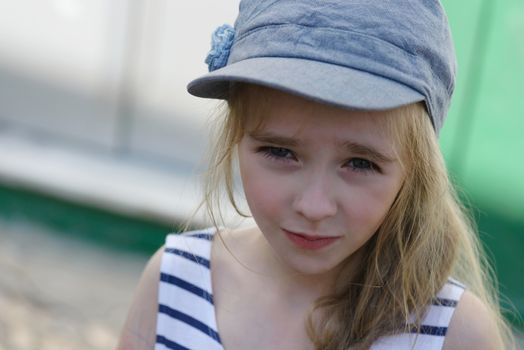 Portrait of cute girl in denim cap looking up seriously.