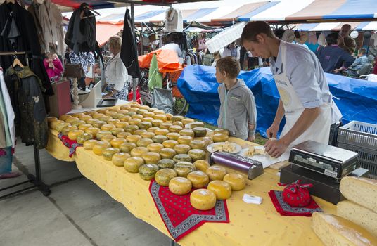 HELLEVOETSLUIS,NETHERLANDS-JULY 12, 2014: Farmer selling dutch cheese at the anual farmers market in Hellvoetsluis on July12,this market is only once a year and selling clothes and fresh food