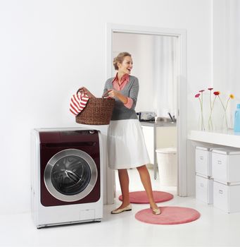 woman doing a housework holding basket of laundry 