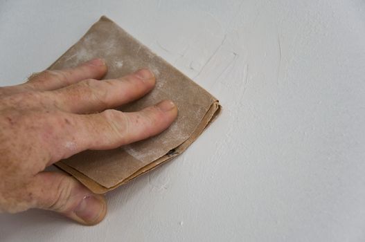 painting renovation -man with sandpaper closeup