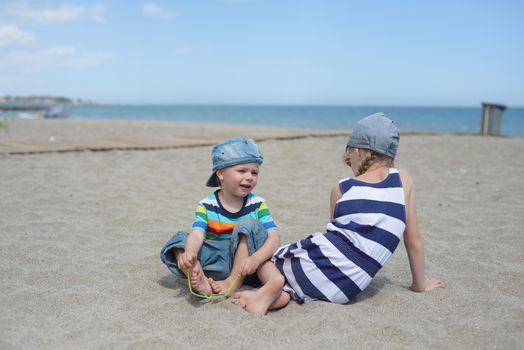 Little boy and girl sitting on the sandy beach