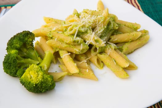 Pasta with broccoli, olive oil and parmesan on the white plate