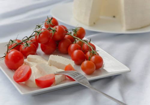 Cherry tomatoes with fresh sicilian cheese on the white square plate