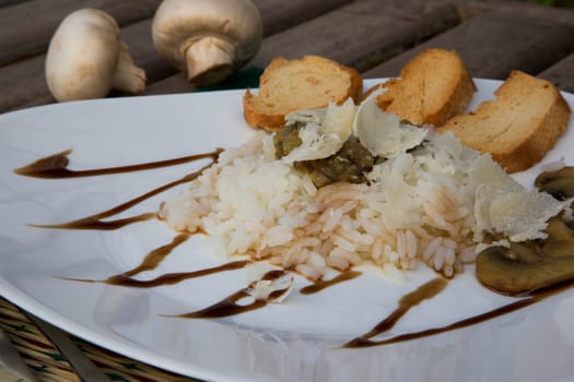 Rice with stewed mushrooms,parmesan and crispy bread on the triangular plate