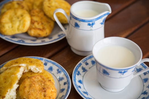 homemade cheese pancake and a cup of warm milk. Panckaes in the background