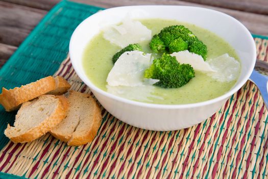 A plate of broccoli cream soup and three pieces of bread