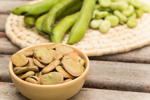 Dried beans in the clay dish. Fresh green beans and bean pods in the background