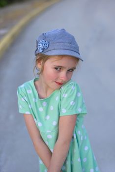 Portrait of cute girl in denim cap and green dress