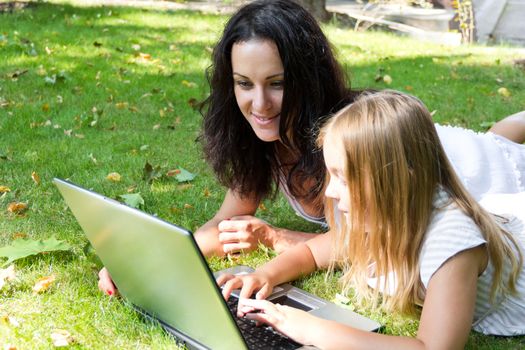 Smiling mother and daughter rest upon herb in summer