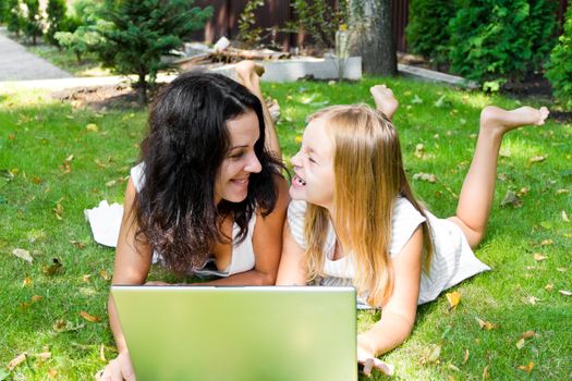 Smiling mother and daughter rest upon herb in summer