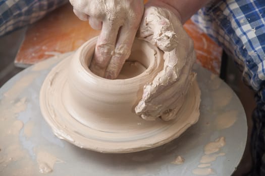 Hands of a potter, creating an earthen jar on the circle