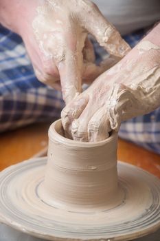 Hands of a potter, creating an earthen jar on the circle