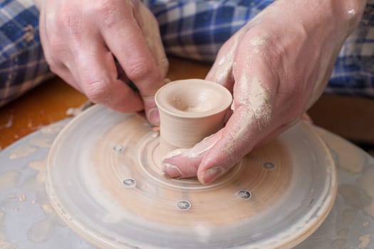 Hands of a potter, creating an earthen jar on the circle