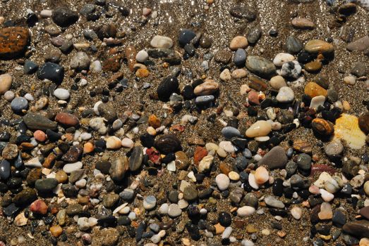 Background of little stones in the shore at the beach