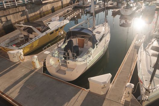 Private boats docked at marina under the orange sunset sunlight.