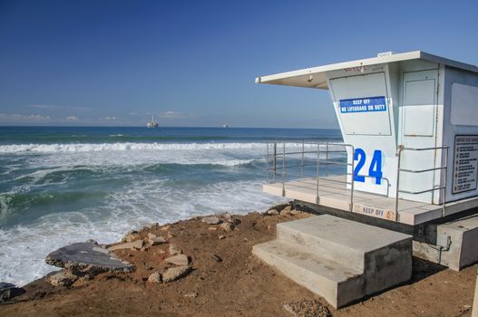 Baywatch lifeguard tower on beach under bright blue sky