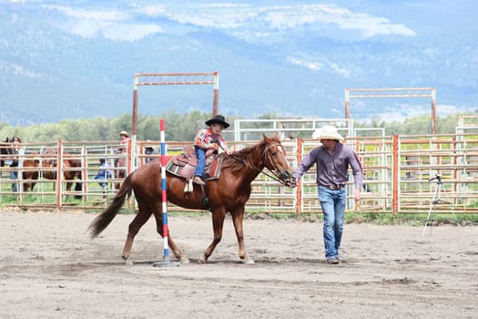 MERRITT, B.c. CANADA - June 14:  Young cowboy and his dad in stake race event at the Little Britches Rodeo June 14, 2014 in Merritt British Columbia, Canada