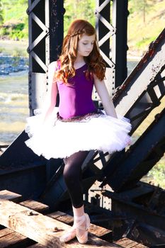 Beautiful girl wearing a white tutu standing on a bridge 