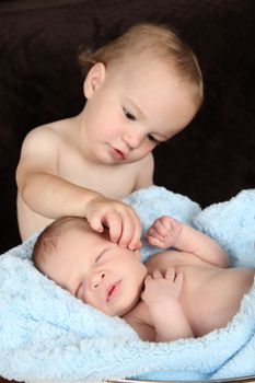 Toddler boy with his baby brother.  FOCUS on baby.