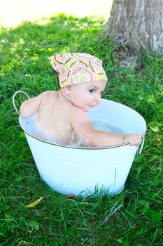 Beautiful baby girl having a bath outdoors
