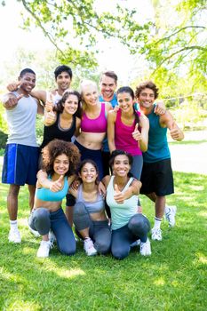 Group portrait of friends in sportswear showing thumbs up at the park