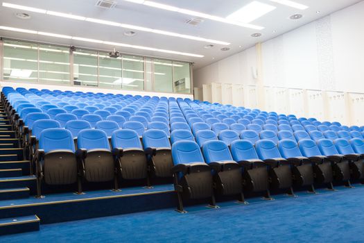 Interior of empty conference hall with blue velvet chairs.