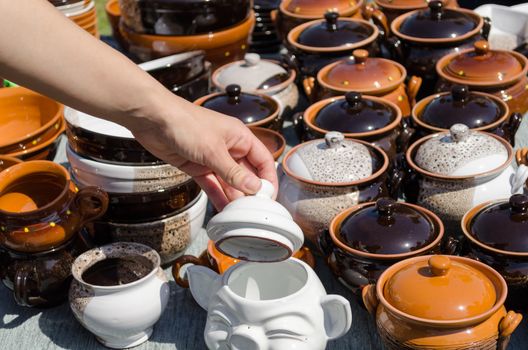 stall full of clay handmade pots and woman hand hold clay lit