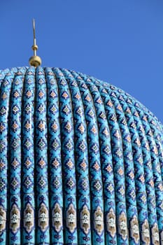 Tiled dome of a mosque with a golden crescent moon on a clear sky frne