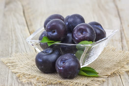 fresh plums in a bowl on wooden background
