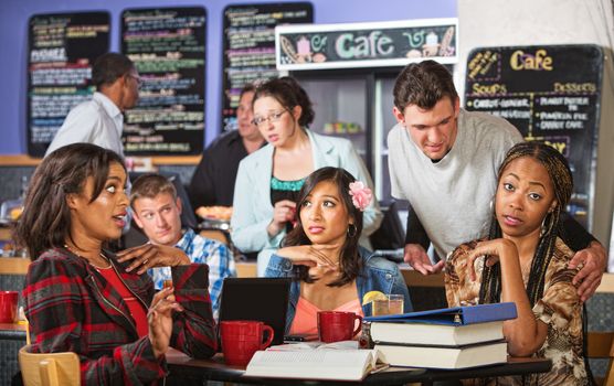 Annoyed beautiful students and suave man in cafe