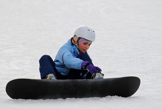 Little girl preparing for the descent of the mountain on a snowboard.