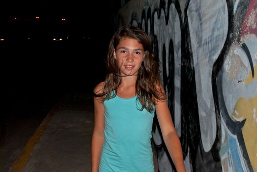 A girl goes through the night embankment of a small town in Greece.