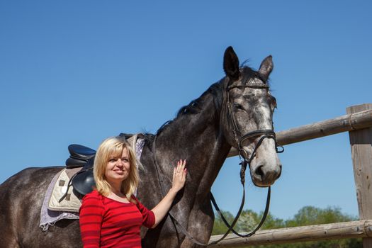 smiling woman with a saddled sports horse