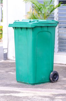 Green garbage, trash bin on side of the building.