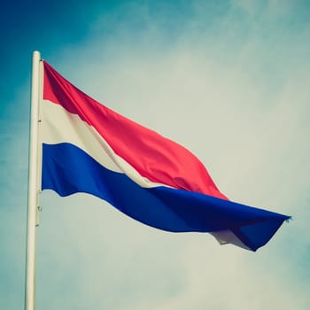 Vintage retro looking Flag of Luxembourg over a blue sky