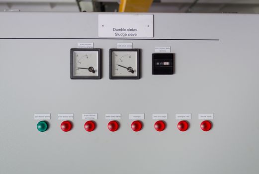 Sludge sieve control panel board with meters and red green lights in water treatment plant.