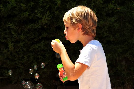 Young boy playing with bubbles in the garden