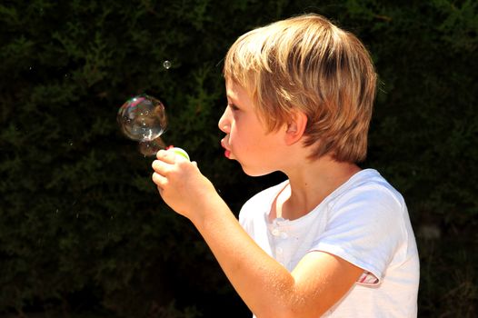 Young boy playing with bubbles in the garden