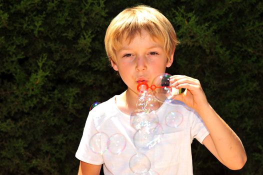 Young boy playing with bubbles in the garden