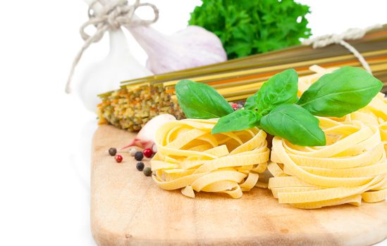 Italian pasta fettuccine nest with fresh basil leaves, on white background