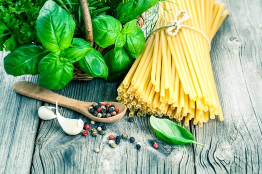 Spaghetti with garlic, peppers, and fresh basil leaves on wooden table