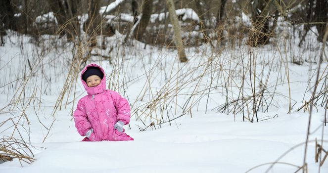 Little winter girl in fairy ice forest running 